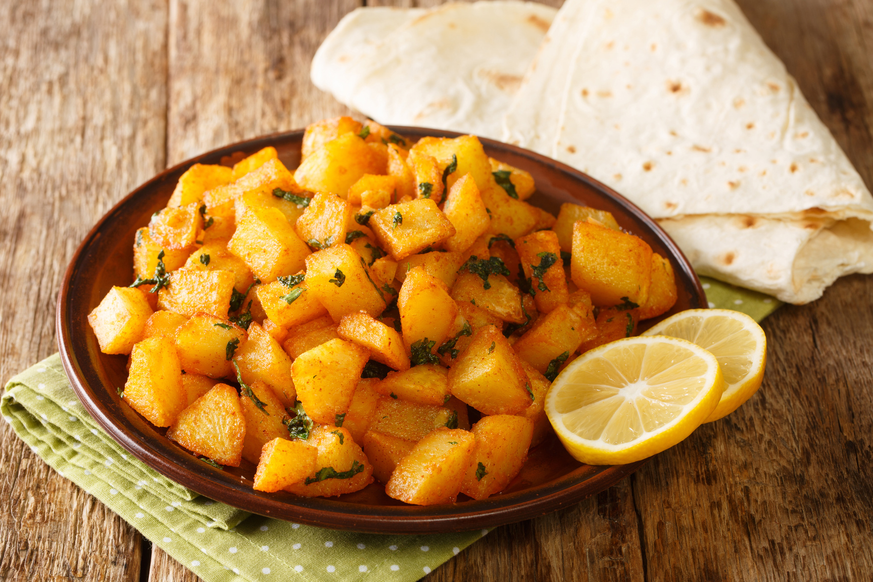 Batata harra or spicy potatoes, is a traditional Lebanese recipe for spicy roasted potatoes close up in the plate. Horizontal